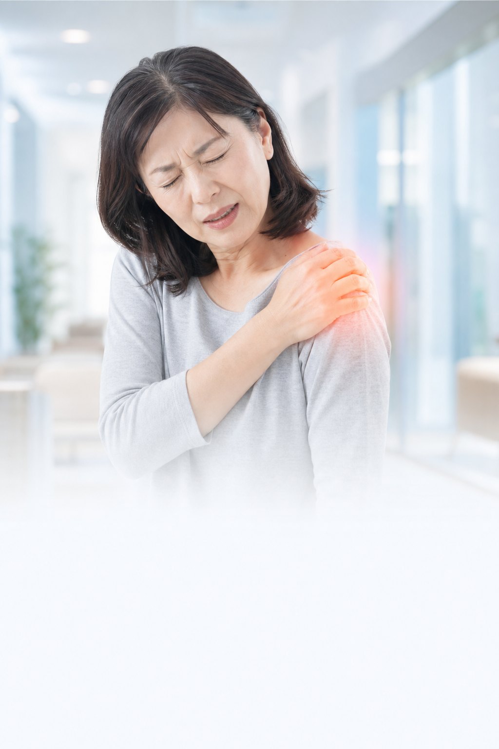 肩の痛みを押さえる50代女性（五十肩のイメージ）